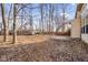 Large backyard with mature trees, lawn covered in leaves, small shed, and patio near the house at 6144 Maple Branch Pl, Indianapolis, IN 46221