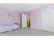 This carpeted bedroom has pink walls, a door to the hallway, and a double-door closet at 6201 S Carroll Rd, Indianapolis, IN 46259