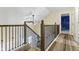 Hallway staircase featuring wood-look floors, an elegant ceiling fan, and decorative wrought iron railing at 6201 S Carroll Rd, Indianapolis, IN 46259