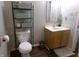 Functional bathroom featuring a toilet, sink with wooden cabinets, and a storage rack for essential items at 6651 Sonesta Dr, Indianapolis, IN 46217