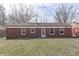 View of the backyard featuring a well-maintained lawn and a red brick home with multiple windows at 7602 E 34Th Pl, Indianapolis, IN 46226