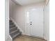 Bright foyer featuring wood-look floors, gray carpeted stairs, and a white front door with glass detail at 8 Greenwood Trail S Dr, Greenwood, IN 46142
