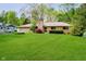 Charming ranch-style home with well-maintained lawn, stone chimney, and mature trees at 8808 Manderley Dr, Indianapolis, IN 46240
