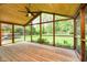 A covered porch with wooden floors and screens, that looks out onto a yard at 8808 Manderley Dr, Indianapolis, IN 46240