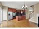 Angle view of kitchen showing hardwood flooring, stainless appliances, cherry wood cabinets, and fireplace in adjacent dining area at 918 Rosalind Pl, Carmel, IN 46032