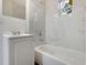 Modern bathroom featuring white marble-style tiling, a tub, and a window at 1209 N Centennial St, Indianapolis, IN 46222