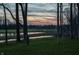 Backyard at sunset, featuring a pond and golf course backdrop, framed by mature trees and colorful sky at 1355 Forest Hills Dr, Westfield, IN 46074