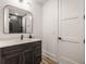 Modern bathroom featuring a single vanity with dark wood cabinets and a large mirror, with a white door nearby at 1355 Forest Hills Dr, Westfield, IN 46074