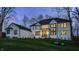 Elegant home exterior with ample windows, set on a manicured lawn and framed by mature trees at dusk at 1355 Forest Hills Dr, Westfield, IN 46074