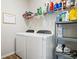 Well-equipped laundry room with white washer and dryer, storage racks, and a framed sign at 15773 Eastpark Dr, Noblesville, IN 46060