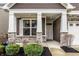 Inviting covered front porch with stone pillars, professional landscaping, and stylish front door at 17099 Cole Evans Dr, Noblesville, IN 46060