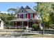 Charming two-story home with a welcoming front porch, a combination of red siding and grey trim, with mature trees and landscaping at 189 S Jefferson St, Martinsville, IN 46151