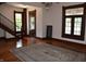 Bright living room featuring a wooden staircase, large windows with stain glass, hardwood floors, and a decorative rug at 189 S Jefferson St, Martinsville, IN 46151