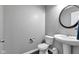 Modern powder room featuring a pedestal sink, toilet, and a round mirror at 281 Dovetree Dr, Danville, IN 46122