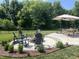 Beautiful backyard with a circular patio, brick fire pit, Adirondack chairs, dining table, and lush green landscaping at 3535 Merchmont Rd, Bargersville, IN 46106