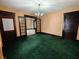 Spacious living room with green carpet, vintage doors, and chandelier lighting at 367 W Broadway St, Shelbyville, IN 46176