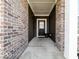 Covered front entry with brick columns and a black front door with glass at 3865 Kensington Dr, Danville, IN 46122