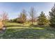 Well-maintained backyard featuring green grass, mature trees, and lush landscaping under a clear sky at 405 Letterman Dr, Brownsburg, IN 46112