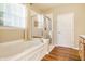 Bathroom featuring a soaking tub, glass-enclosed shower, and wood-look flooring at 405 Letterman Dr, Brownsburg, IN 46112