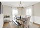 Bright dining room featuring modern chandelier, wood table with bench and upholstered chairs, and large windows at 491 Tracewood Bnd, Greenfield, IN 46140