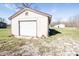 A small garage with a white door has a simple design and is surrounded by a grassy yard at 5010 S 550 W, Columbus, IN 47201