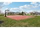 Red basketball court surrounded by grass, trees, gazebo, and playground at 5520 N Woodside Ct, McCordsville, IN 46055
