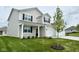 Inviting two-story home with a covered front porch, enhanced by lush landscaping and a green lawn at 5908 Agogo Way, Greenwood, IN 46143