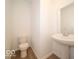 Compact powder room featuring a pedestal sink, neutral walls, and stylish laminate flooring at 5908 Agogo Way, Greenwood, IN 46143