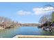 Panoramic lake view showcasing waterfront homes along a tree-lined shore under a bright blue sky with fluffy white clouds at 6198 Grosbeak Dr, Nineveh, IN 46164