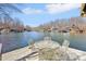 Outdoor dining area with metal table and chairs set on a wooden deck overlooking a serene lake with waterfront homes at 6198 Grosbeak Dr, Nineveh, IN 46164