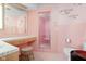 Retro pink bathroom featuring a vanity, stool, tile shower, and decorative metal fish at 6461 Sunset Ln, Indianapolis, IN 46260