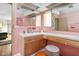 Retro pink bathroom with vanity, sink, shower, mirror, and stool at 6461 Sunset Ln, Indianapolis, IN 46260