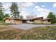 Ranch home featuring a stone facade, three car garage, and expansive driveway at 6461 Sunset Ln, Indianapolis, IN 46260
