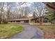 Inviting ranch home with a stone facade, mature trees, and a long driveway to attached garage at 6461 Sunset Ln, Indianapolis, IN 46260