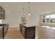 Modern kitchen island with sink, stainless steel appliances and hardwood floors, with natural light from the window at 7158 Rose Hill Ave, Brownsburg, IN 46112