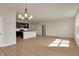 Open concept living room with a modern chandelier, dark wood kitchen, and large windows for natural light at 7158 Rose Hill Ave, Brownsburg, IN 46112