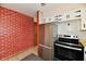 Kitchen with stainless steel fridge and oven, white cabinets, brick wall, and tile flooring at 7953 Forest Park Dr, Indianapolis, IN 46217