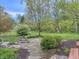 Serene backyard view featuring a stone patio, lush landscaping, and mature trees at 8510 N Park Ave, Indianapolis, IN 46240