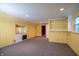 Finished basement with yellow walls, neutral carpet, built-in shelves, and access to another room at 8510 N Park Ave, Indianapolis, IN 46240