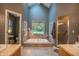 Soaking tub in a luxury bathroom featuring neutral tile, vaulted ceilings, and a scenic view at 8510 N Park Ave, Indianapolis, IN 46240