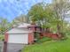 Exterior featuring a brick and white garage with a deck and well-manicured landscaping at 8510 N Park Ave, Indianapolis, IN 46240
