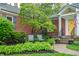 Charming brick home features a yellow front door and manicured landscaping with lush greenery at 8510 N Park Ave, Indianapolis, IN 46240