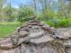 Backyard stone waterfall with a charming rabbit statue and verdant landscaping at 8510 N Park Ave, Indianapolis, IN 46240