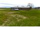 Exterior shot of the backyard of the single-story home with a metal roof and propane tank at 10966 W State Road 142, Quincy, IN 47456