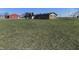 A large yard highlights the home's exterior, complemented by a red barn in the background at 10966 W State Road 142, Quincy, IN 47456