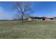 A large tree sits in the yard while the home's exterior features a red barn, surrounded by green grass at 10966 W State Road 142, Quincy, IN 47456