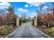 Grand entrance featuring a long driveway leading to an elegant home, framed by brick pillars and lush greenery at 11796 Sycamore St, Zionsville, IN 46077
