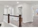 Upstairs hallway featuring a wooden railing, carpeted floor, and a view to multiple doorways with an abundance of light at 16429 Mount Logan Rd, Noblesville, IN 46060