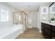 A bright bathroom featuring a large soaking tub, glass shower, and double vanity with dark cabinetry at 19966 Chatham Green Dr, Westfield, IN 46074