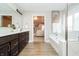 A bright bathroom featuring a soaking tub, glass shower, and double vanity with dark cabinetry at 19966 Chatham Green Dr, Westfield, IN 46074